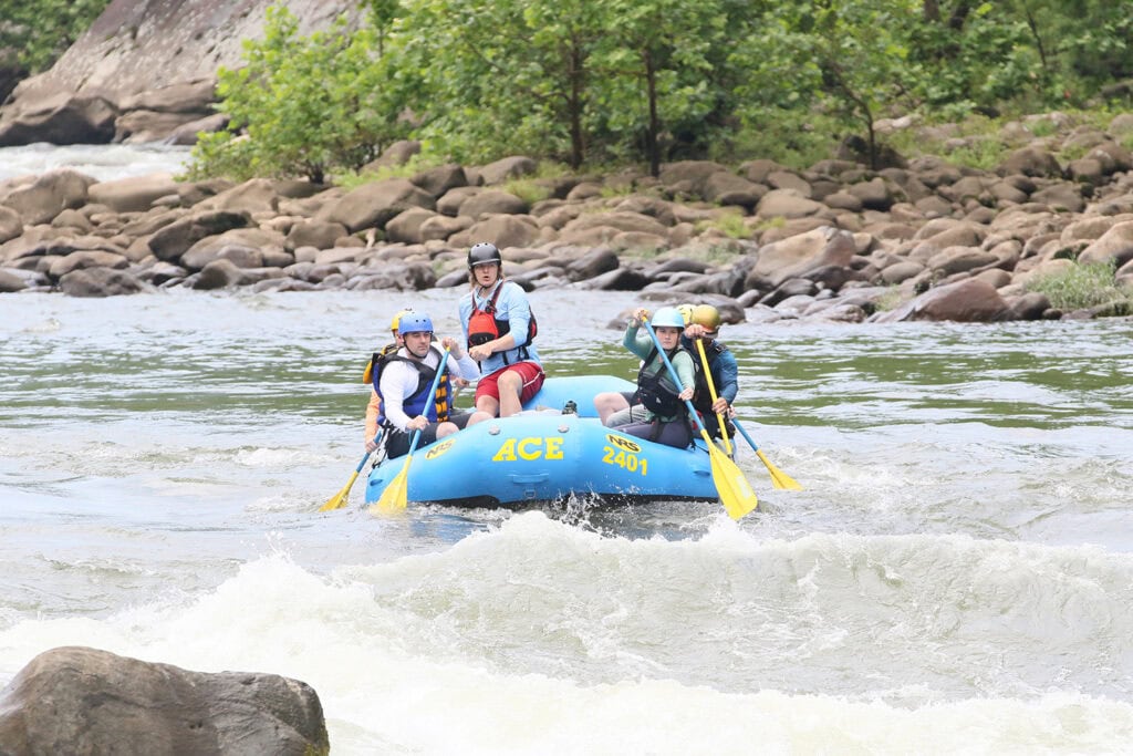 Family navigating rapids during New River Gorge whitewater rafting trip