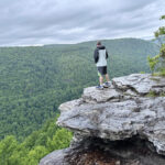 Man standing on a large rock taking in the views of the valley at Lindy Point in WV