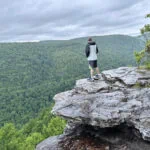 Man standing on a large rock taking in the views of the valley at Lindy Point in WV